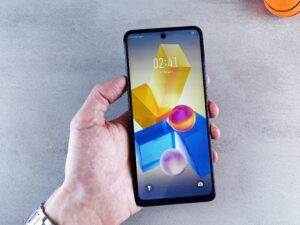 A hand holding a smartphone displaying colorful geometric shapes on the screen.