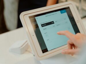 A person uses a tablet-based point-of-sale system by selecting options on a touchscreen device.